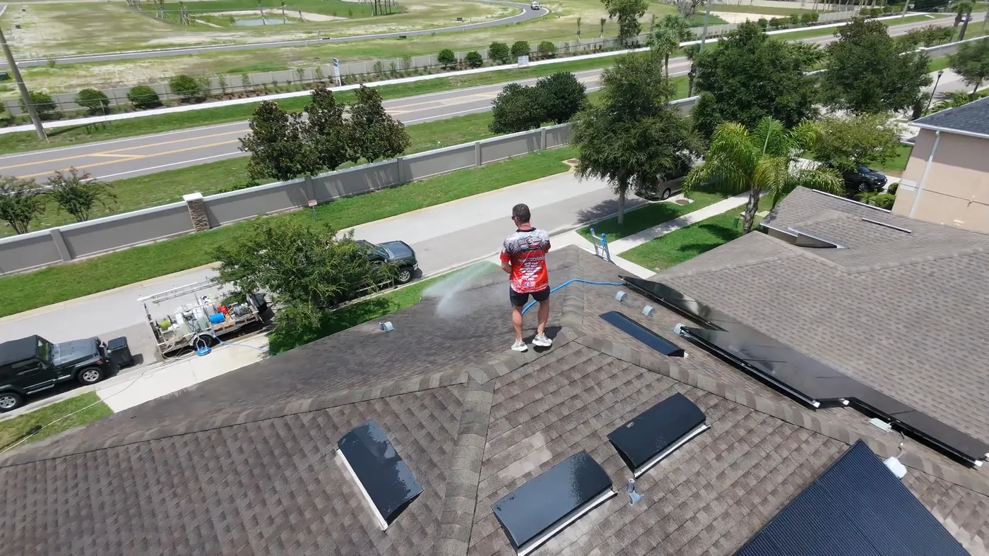 Aerial view of an Iron Shield technician treating discoloured sections of a home shingle roof